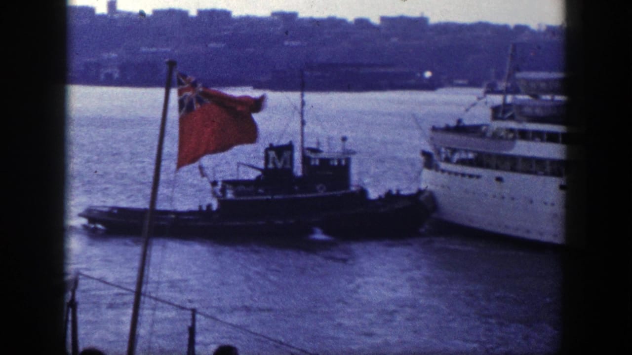 Tugboat beside a large ship with a red ensign flag in the foreground.