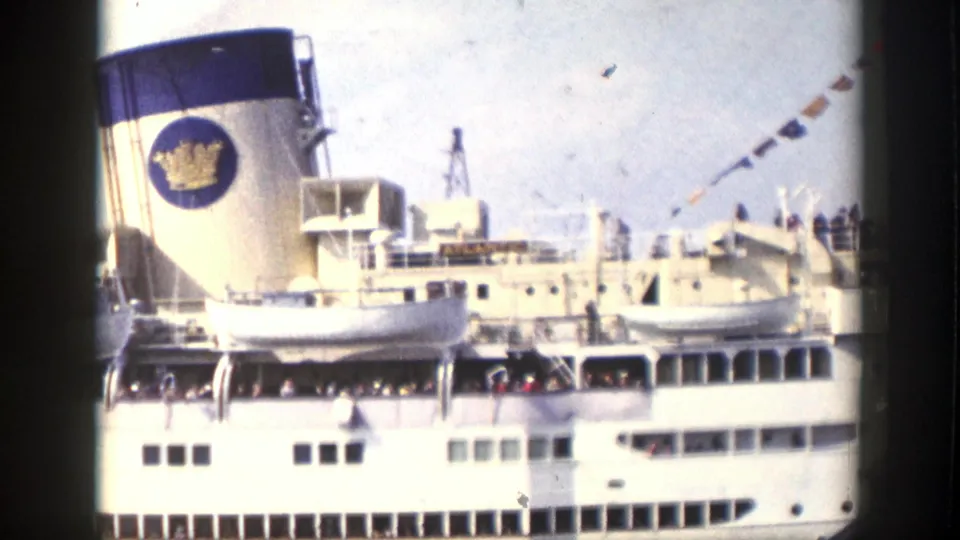 A large white cruise ship section shows lifeboats, a funnel emblem, deck structures, and bunting in faded 8mm color.