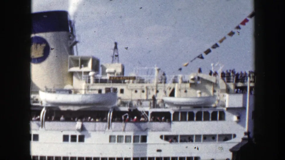 The ship exterior fills the frame with lifeboats, railings, passengers in the distance, bunting, and the visible name ATLANTIC.