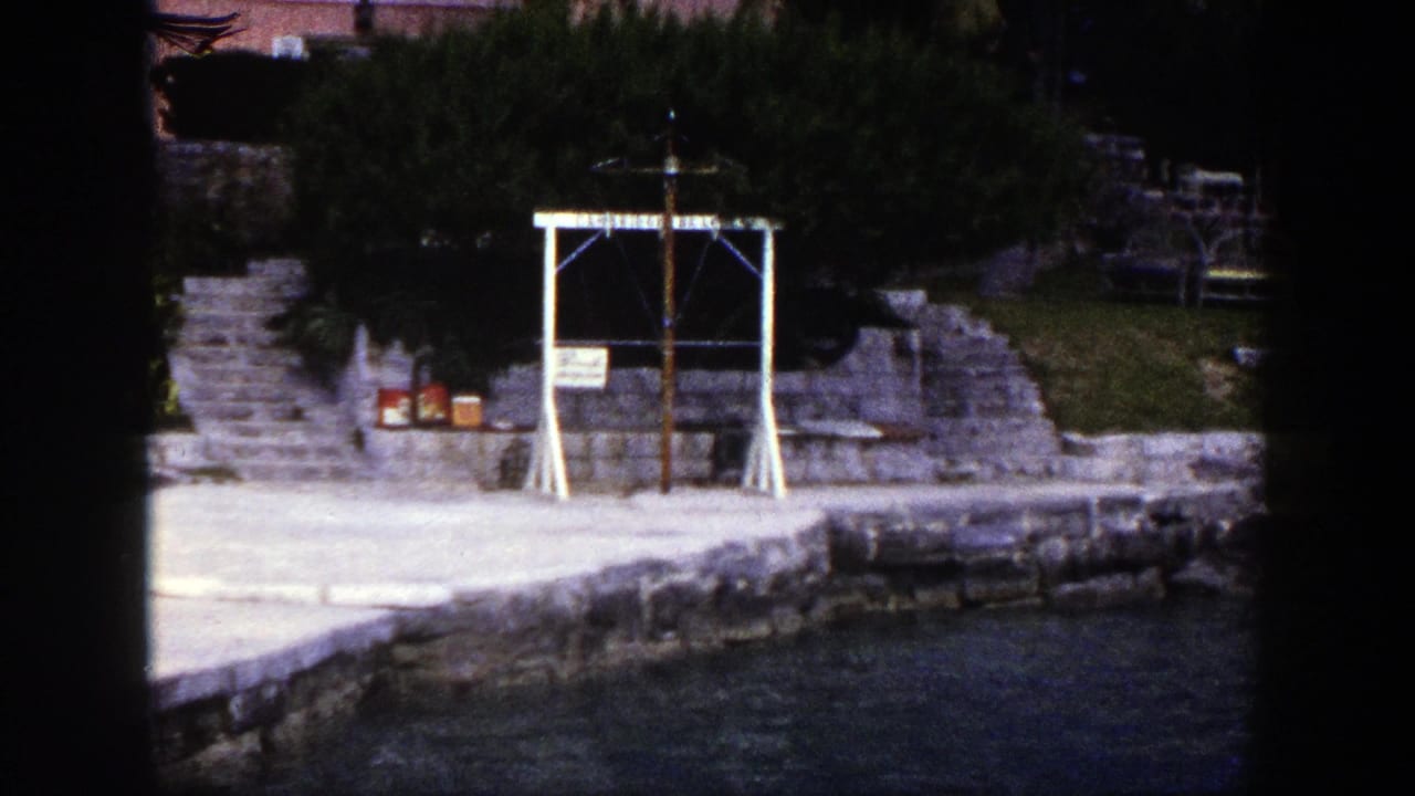 Stone waterfront with calm water and a white cross-like frame near steps.