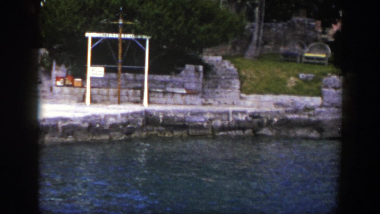 Waterfront embankment with stone wall, trees, benches, and a white rectangular frame.