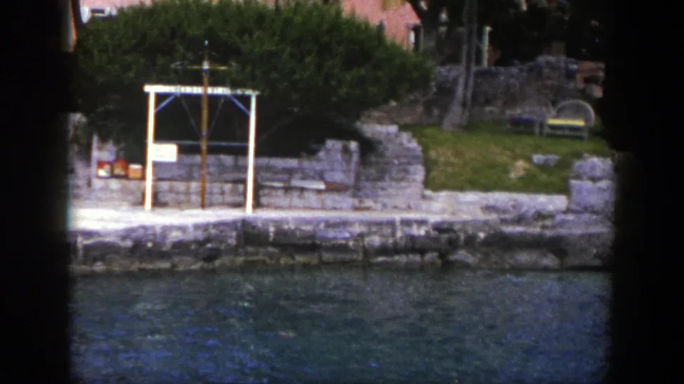 1948 New York 8mm frame with a stone shoreline, white-framed feature, steps, trees, benches, and blue-green water.