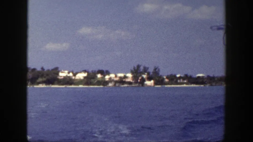 1948 New York water-travel frame with rippled blue water, distant white buildings, trees, and soft motion blur.