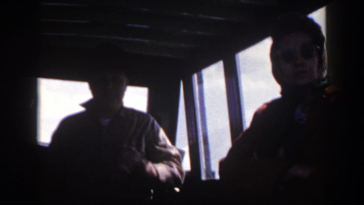 Silhouetted person inside a boat cockpit beside bright rectangular windows.