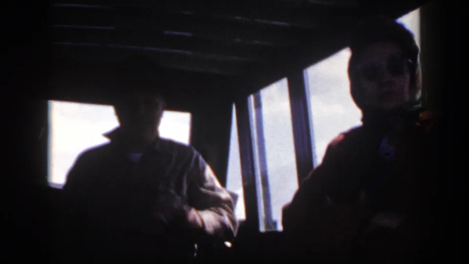 A silhouetted adult stands or leans inside a New York boat cockpit in 1948, with bright daylight through the windows.