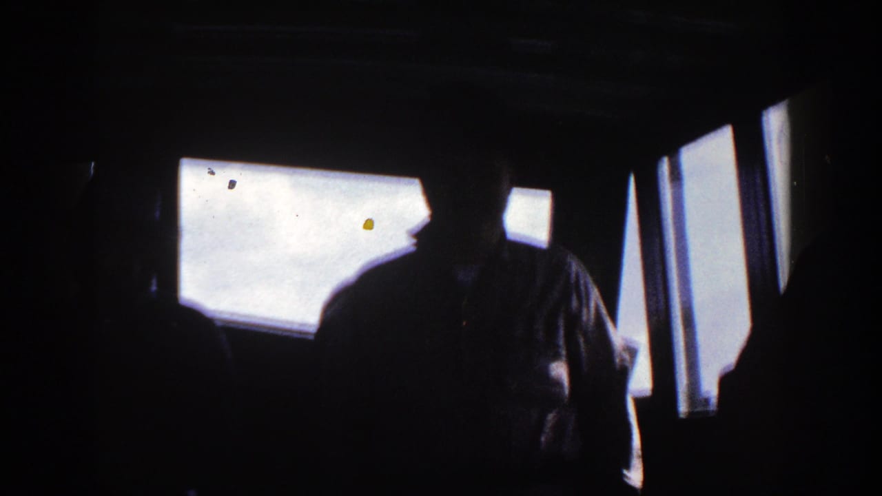 Central silhouetted figure in a dim boat cockpit with windows behind.