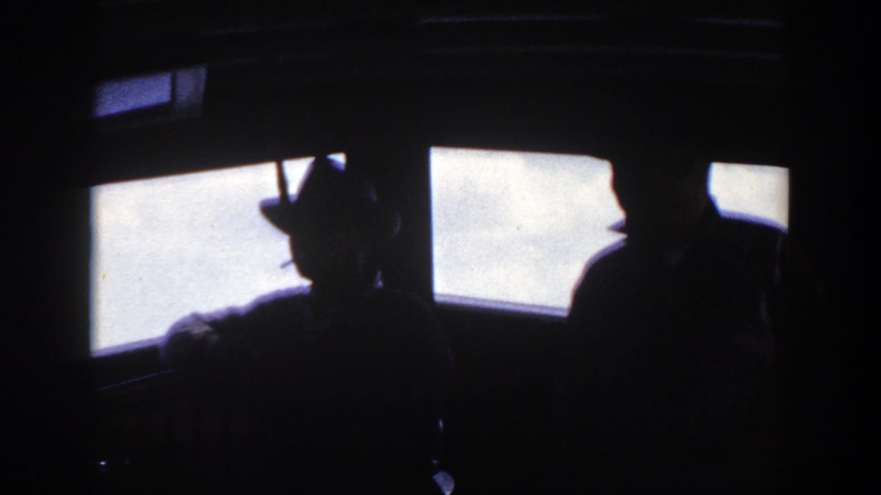 1948 8mm home-movie frame from New York metadata showing passengers in silhouette beside bright ship windows.
