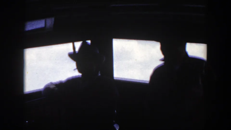 1948 8mm home-movie frame from New York metadata showing passengers in silhouette beside bright ship windows.