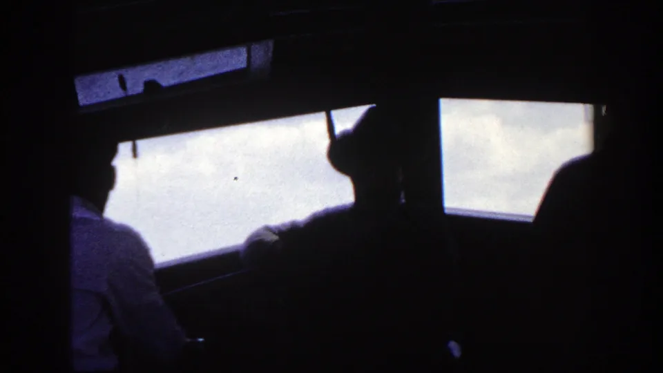 A 1948 8mm frame shows several ship passengers in period clothing silhouetted against bright windows.
