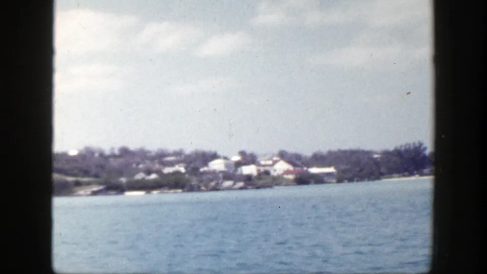 Final 1948 New York coastal frame with open water, distant houses, trees, and soft 8mm color.