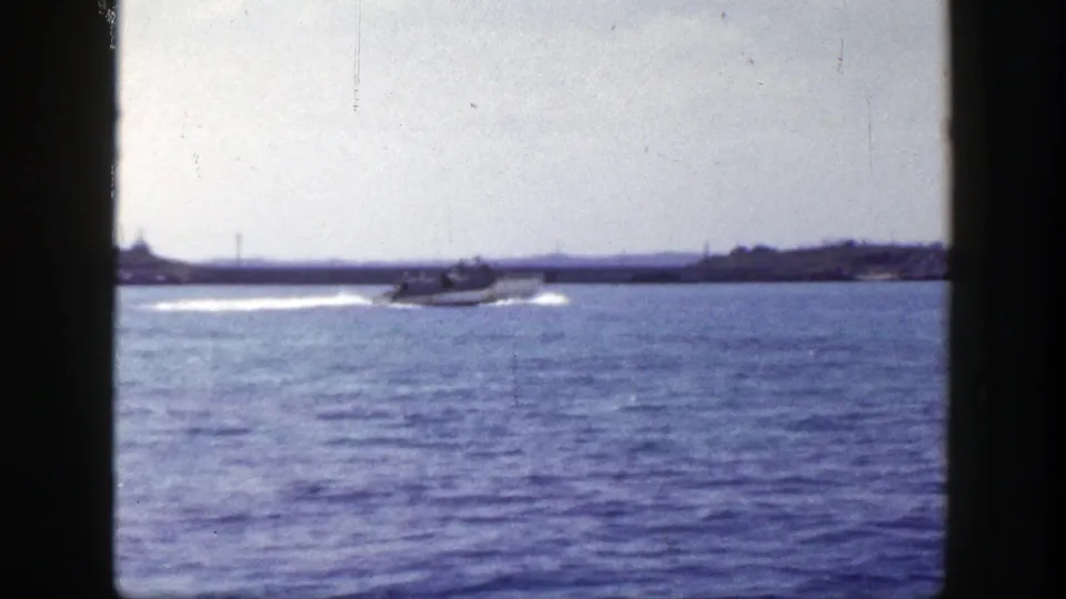 1948 New York 8mm still with a small motorboat near the coast, seen through grainy home-movie framing.