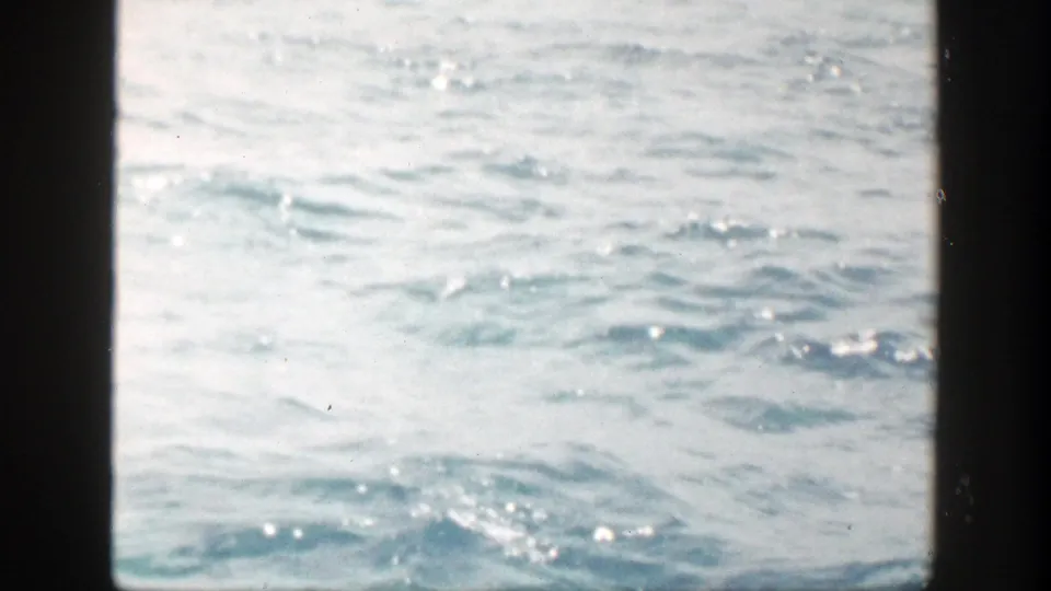 1948 New York boating frame focused on shimmering open water, partly bordered by dark boat structure, with no clear person centered in view.