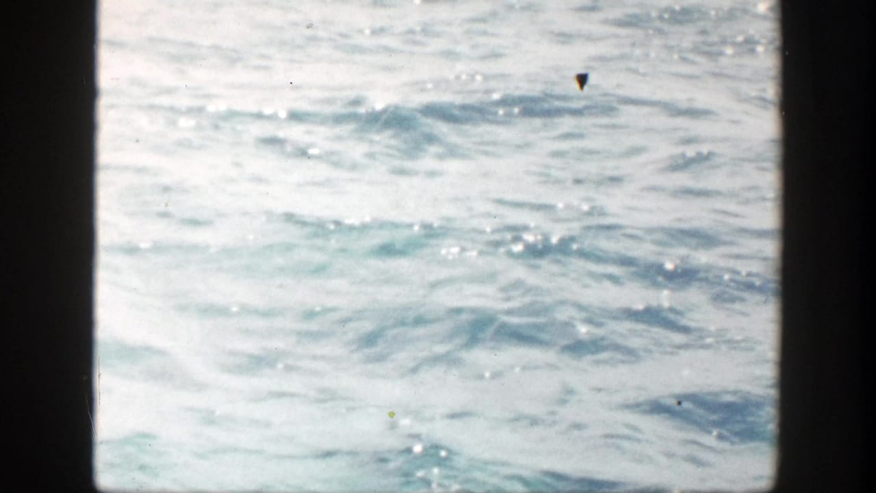 Choppy pale seawater seen through dark 8mm film borders.