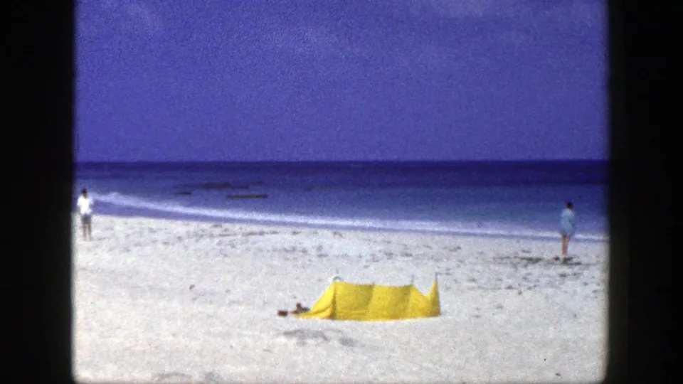A yellow tent rests on a New York beach in 1948, with two distant figures spaced along the shoreline.