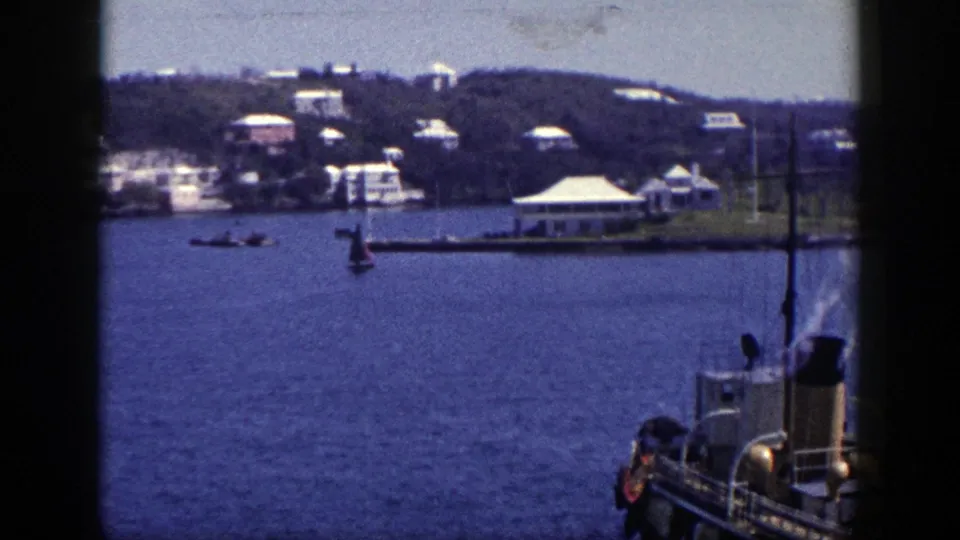 1948 New York boat-view frame showing a waterfront, small boats, hillside buildings, and part of the filming vessel at right.