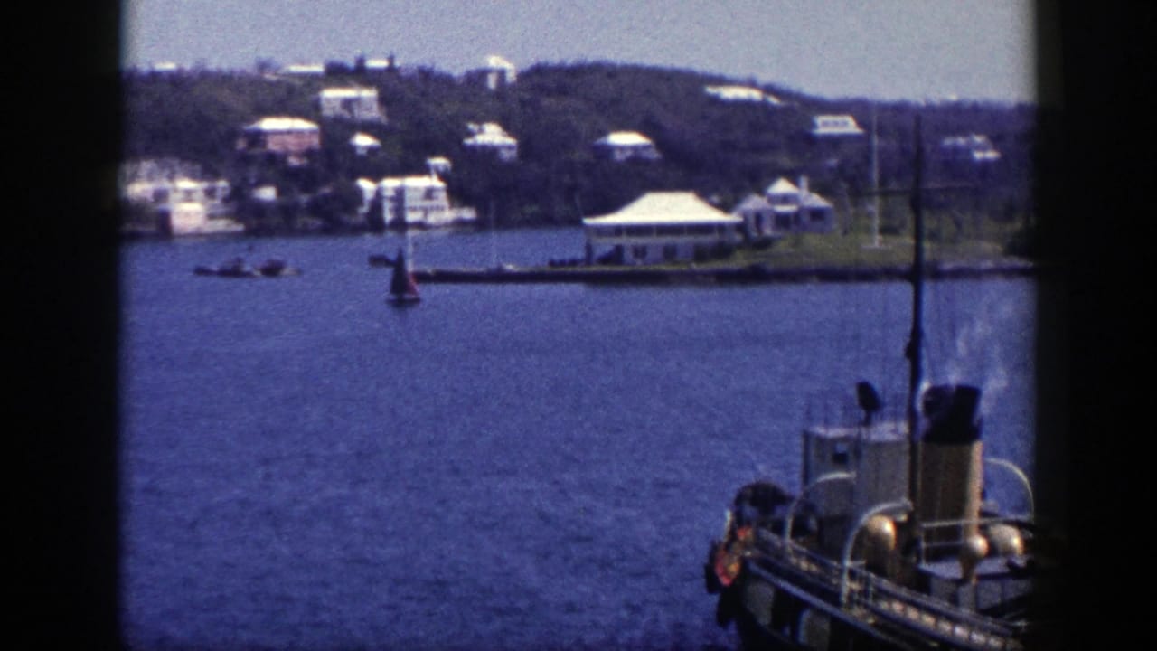 1948 8mm view of a steam boat on New York harbor water, with a small sailboat and hillside buildings in the distance.