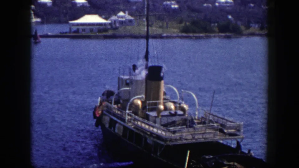 The vessel is centered in a 1948 New York harbor view, with railings, stack, and distant waterfront visible through soft 8mm grain.