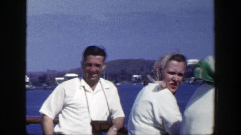 The group shifts position in this 1948 New York home-movie frame, with blue water, shoreline buildings, and bright sunlight visible.