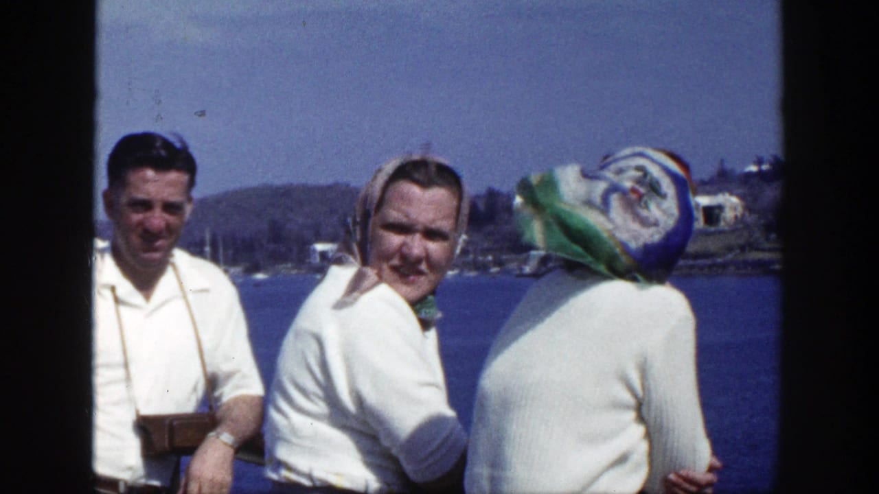 1948 New York home-movie frame of three adults by a lake, including a man with a camera and two women in headscarves.