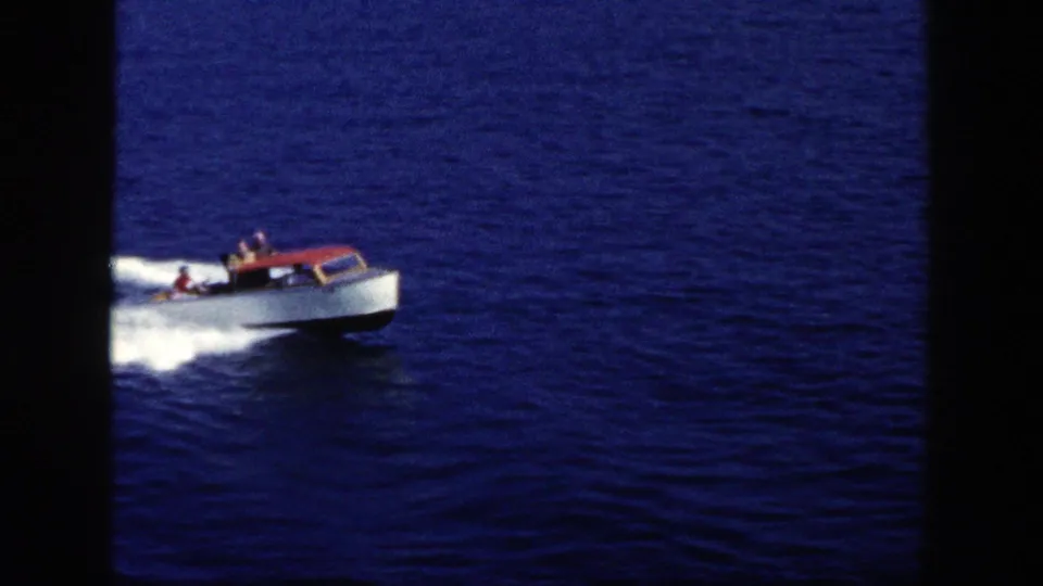 1948 New York home-movie frame of a small motorboat moving across a blue lake under clear daylight.