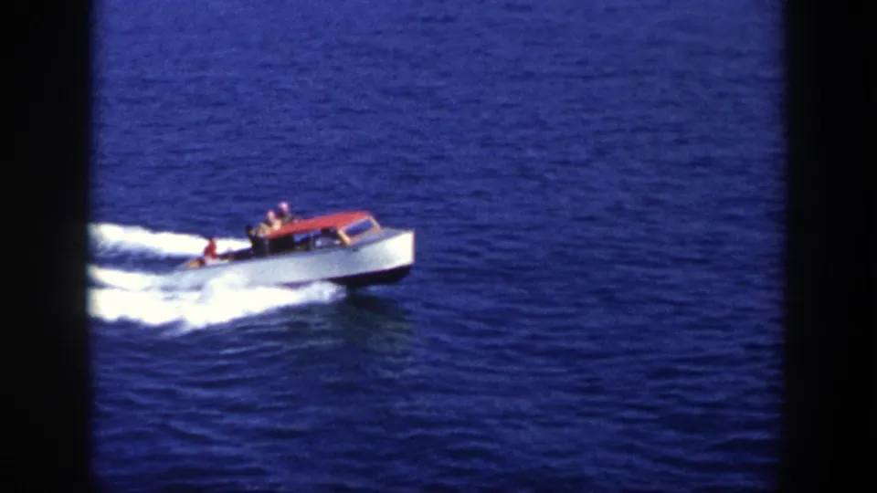 1948 New York home-movie frame showing a red and white motorboat moving across open blue water with passengers visible.