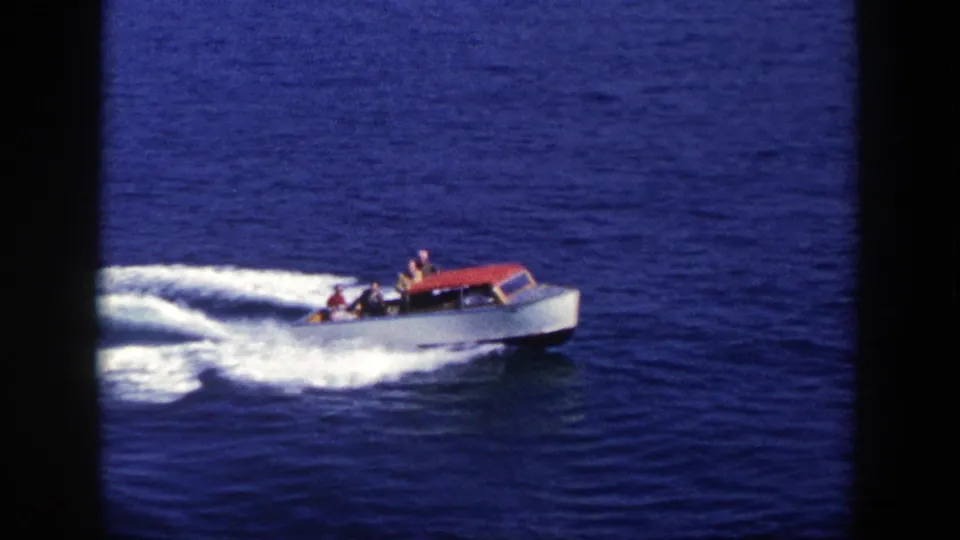 A red-topped white motorboat carries passengers across open water in this 1948 New York 8mm frame.