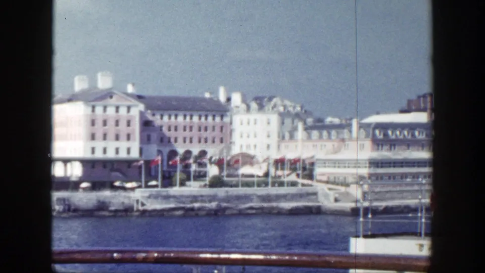 New York waterfront architecture in 1948 passes through the frame with flags, blue water, and ship hardware visible.