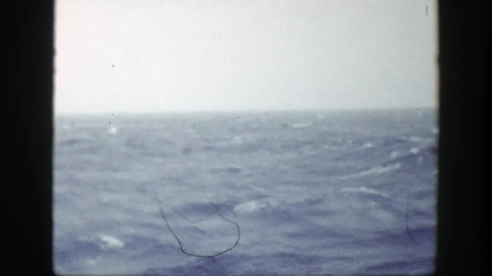 Open ocean fills the frame, with low rolling waves beneath a pale sky in the 1948 New York home-movie clip.