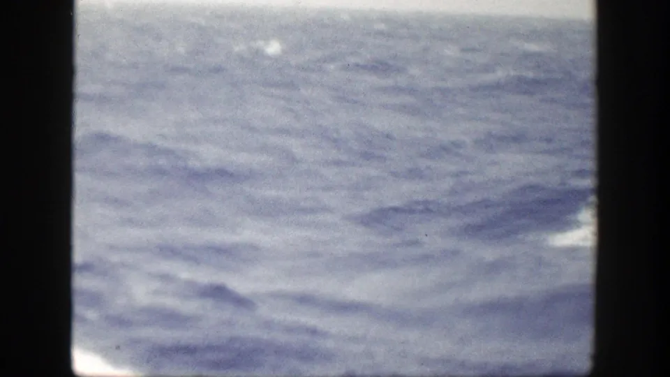 1948 8mm frame showing rough open water from a vessel, with the bow edge and dark scan borders visible.