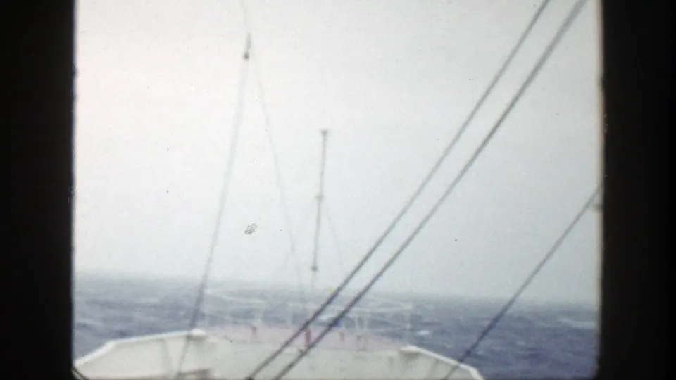 Faded 1948 home-movie frame of the ship bow, antenna mast, and rigging in bright overcast conditions at sea.