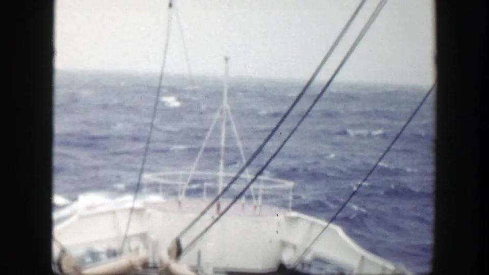 1948 maritime home-movie view of the forward deck and rigging as the vessel moves through rough blue water.