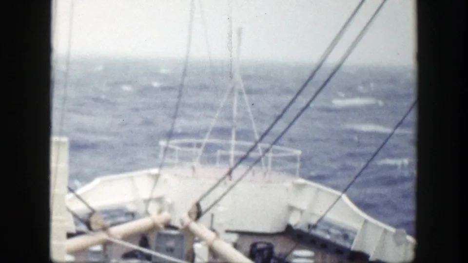 1948 home-movie still of a vessel's bow and forward deck framed by dark film edges as waves move ahead.