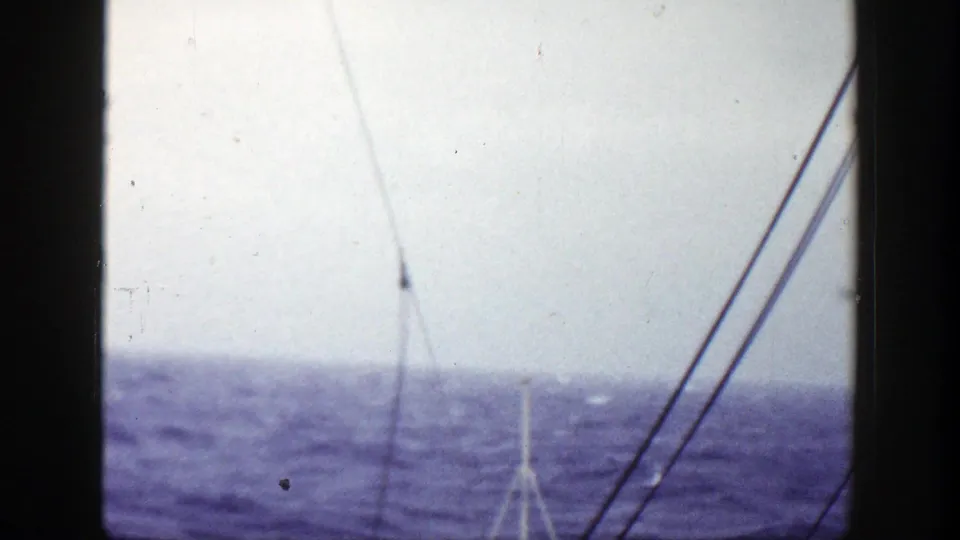 1948 8mm frame showing ship rigging and mast lines above rough blue sea, with the bow partly visible at the lower edge.