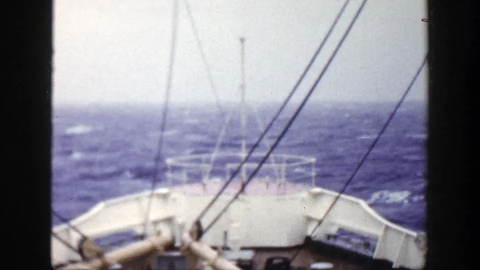 1948 8mm frame from a ship deck, showing white railings, deck fittings, rigging and choppy ocean water.