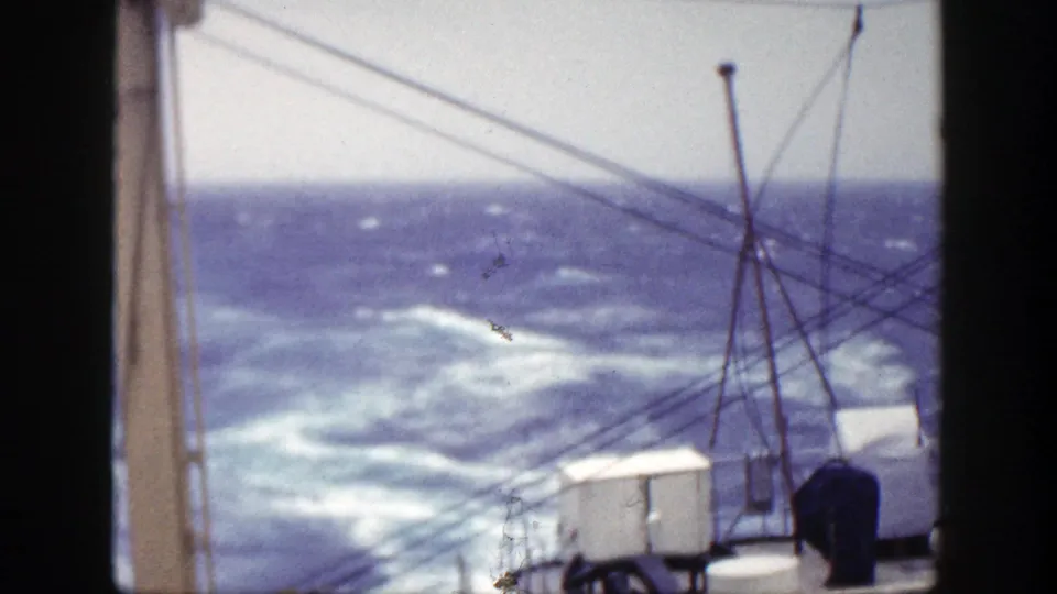 Shipboard 8mm frame showing turbulent blue water with whitecaps and rigging in the foreground, associated with 1948 New York metadata.