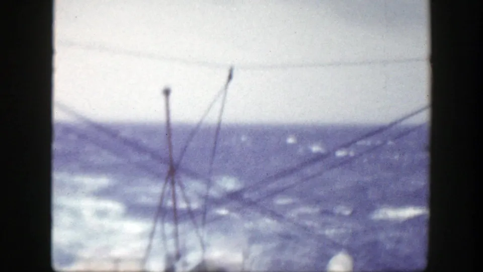 Soft 1948 8mm frame from a ship near New York, showing rigging in the foreground and rough ocean water beyond.