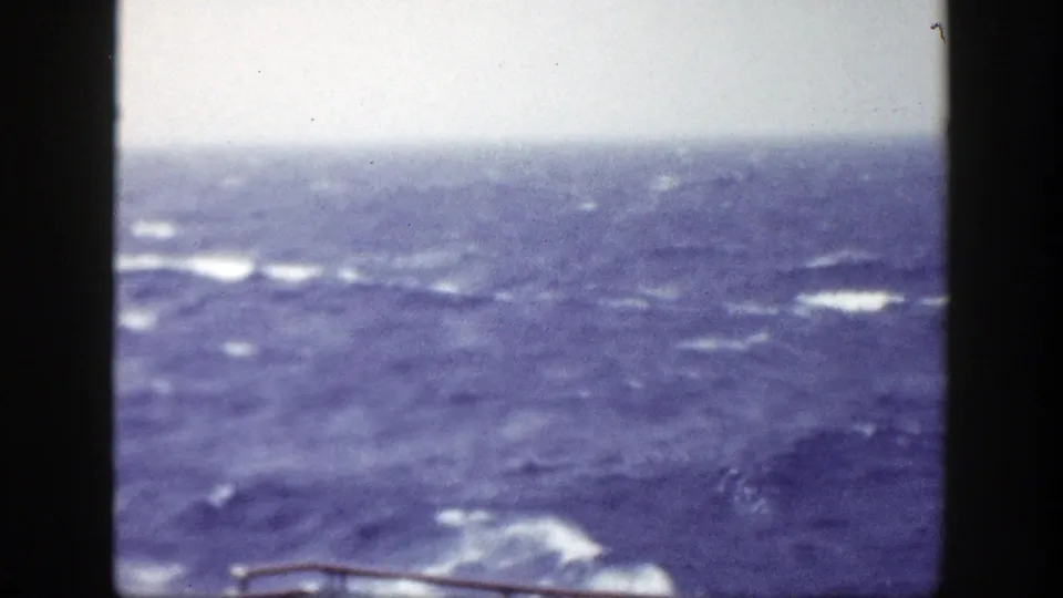 1948 New York-area home-movie view of rough blue ocean and whitecaps from a vessel deck, framed by dark vertical structures.