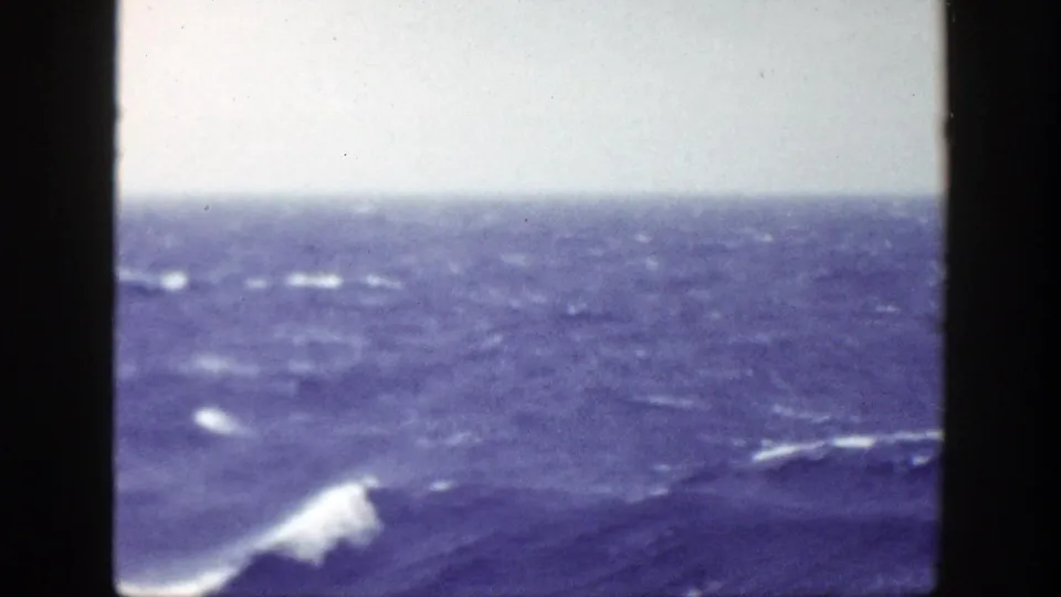 A larger whitecap crests in the foreground during a rough 1948 ocean passage near New York, filmed from the vessel deck.