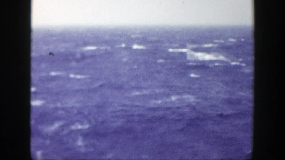 Soft, grainy 8mm frame of choppy blue sea with whitecaps and no visible people, vessels, or shoreline.