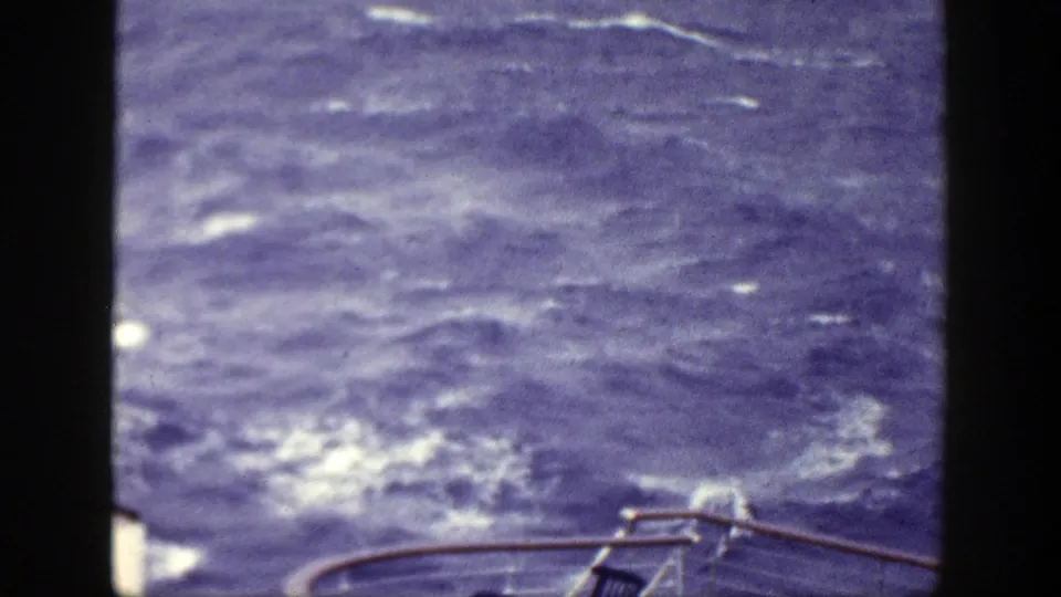 1948 8mm frame showing churning blue water, whitecaps, and a curved ship railing along the lower edge.