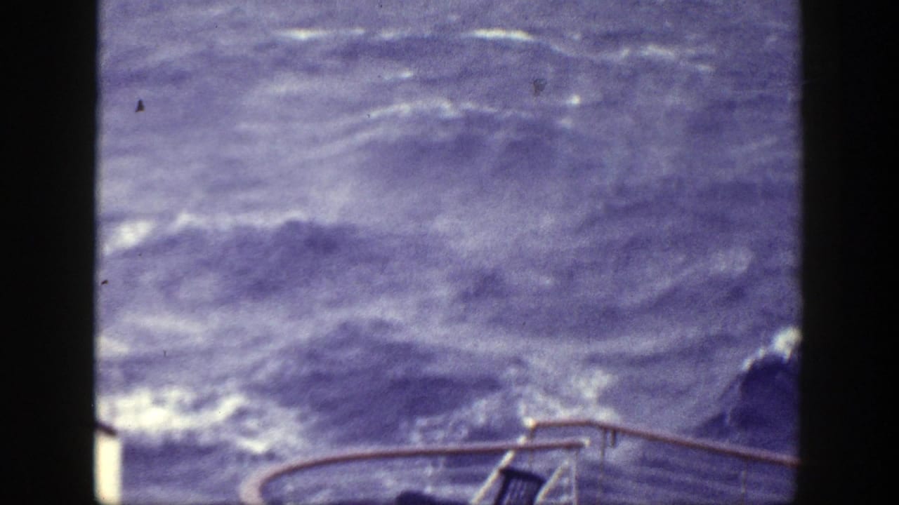 Choppy sea and whitecaps seen past a boat railing and dark film gate edges.