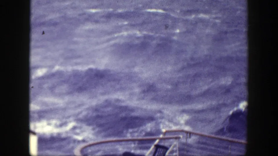 1948 8mm home-movie frame of rough open water viewed from a boat near New York, with railing at the lower edge.