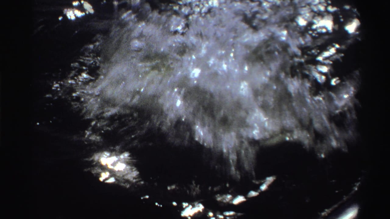 1969 Nigeria 8mm frame showing turbulent water beside a small boat during a fishing catch, with bright sun glare and dark handheld framing.