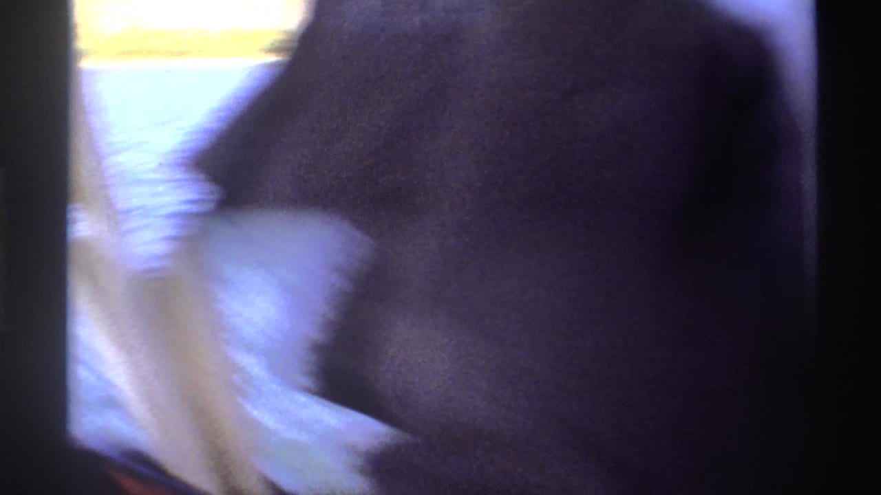 1969 Nigeria 8mm frame showing a blurred close view from a boat, with water, dark clothing, and film-edge shadow visible.