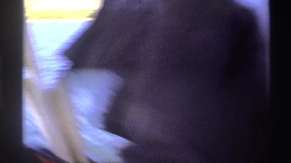 1969 Nigeria 8mm frame showing a blurred close view from a boat, with water, dark clothing, and film-edge shadow visible.