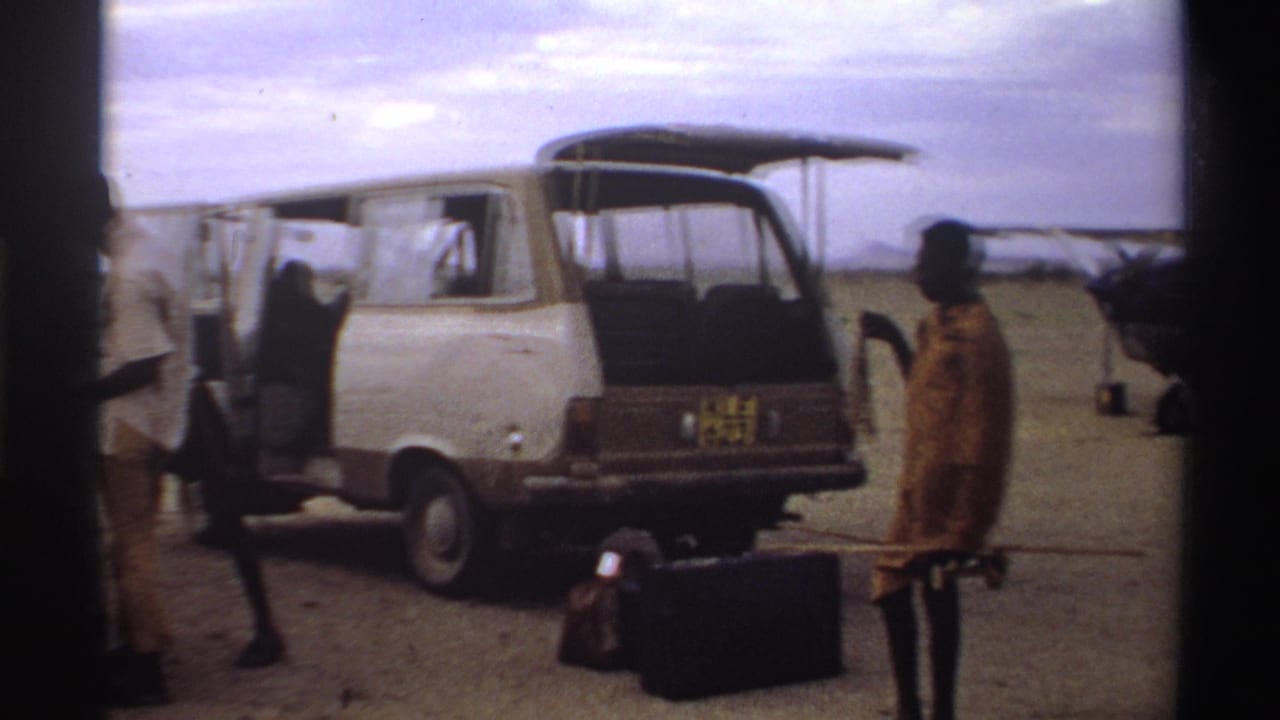 1969 Nigeria travel scene with an open van, luggage on the ground, standing figures and small aircraft on a dusty airfield.