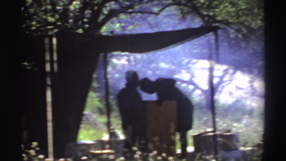 A silhouetted person leans over materials beneath the makeshift tent in the Nigeria 1969 home-movie footage.