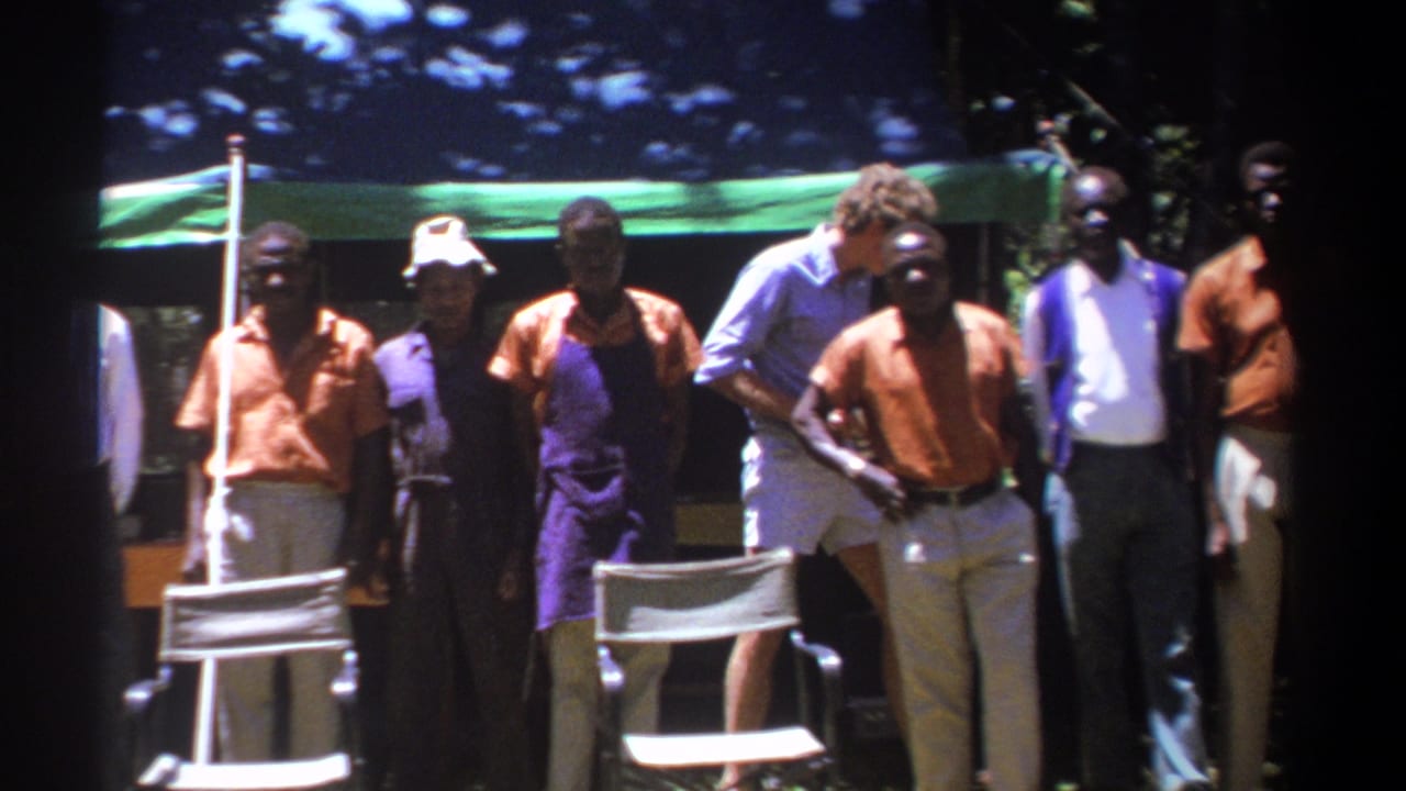 Men in matching clothing stand in a line under a green canopy.