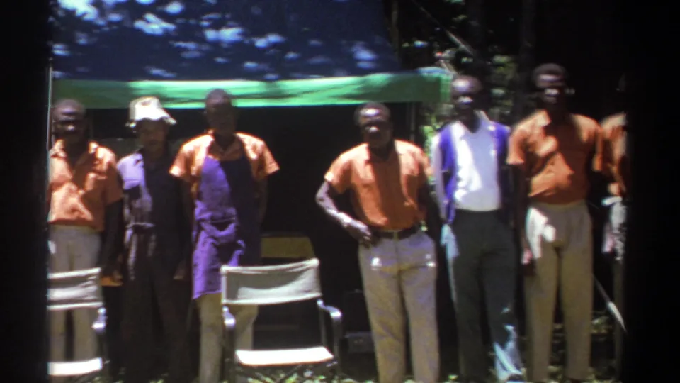The 1969 Kenya footage shows adults shifting positions beneath a green canopy, with chairs and trees in the background.