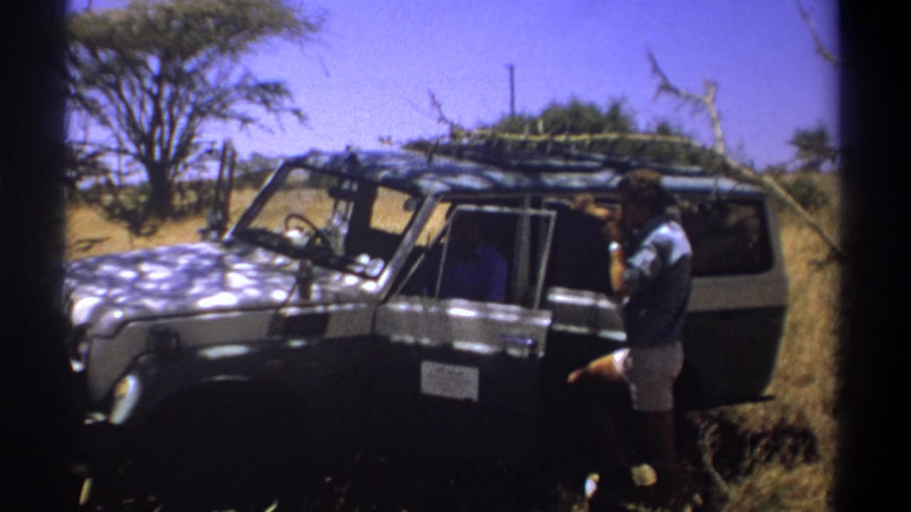 Man beside a parked safari vehicle, with another person visible inside.